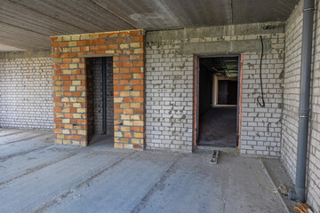 Renovation of new housing in the apartment. Unfinished interior of an apartment under construction with a gray concrete wall in a multi-storey residential building on a construction site.