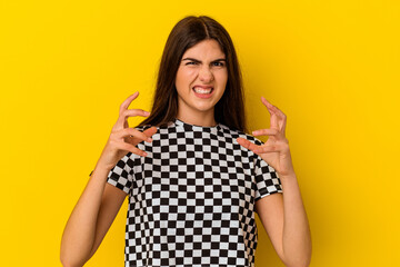 Young caucasian woman isolated on yellow background upset screaming with tense hands.