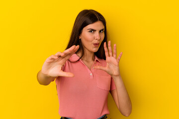 Young caucasian woman isolated on yellow background rejecting someone showing a gesture of disgust.