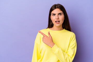 Young caucasian woman isolated on purple background pointing to the side