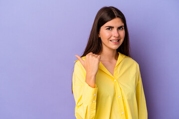 Young caucasian woman isolated on purple background shocked pointing with index fingers to a copy space.