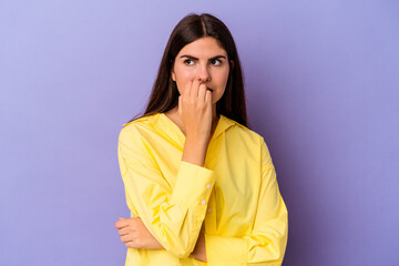 Young caucasian woman isolated on purple background biting fingernails, nervous and very anxious.