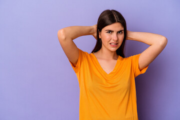 Young caucasian woman isolated on purple background touching back of head, thinking and making a choice.
