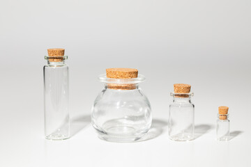 Small, glass, empty bottles of various shapes closed with a natural stopper. Grey background. - 435213099