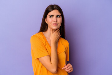 Obraz premium Young caucasian woman isolated on purple background suffers pain in throat due a virus or infection.