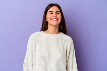 Fototapeta premium Young caucasian woman isolated on purple background laughs and closes eyes, feels relaxed and happy.