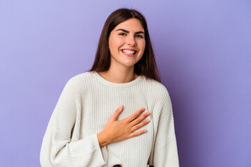 Young caucasian woman isolated on purple background laughs out loudly keeping hand on chest.