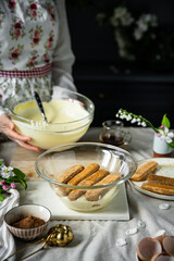 Process of making tiramisu. Layering mascarpone cream and ladyfingers soaked in coffee with alcohol .