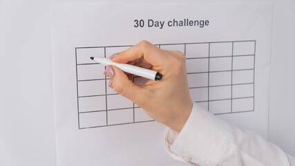 Cropped view of woman writing check marks in boxes of 30 days challenge