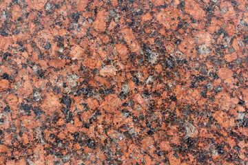 Abstract textured red granite background. Close-up view. Construction industry. Granite is rocks that is composed mostly of coarse-grained quartz and feldspars in varying proportions.