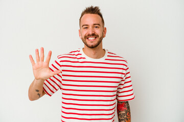Young tattooed caucasian man isolated on white background smiling cheerful showing number five with...
