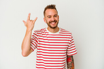 Fototapeta premium Young tattooed caucasian man isolated on white background showing rock gesture with fingers