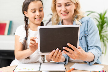 Mother and daughter websurfing on internet with tablet