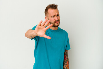 Young tattooed caucasian man isolated on white background rejecting someone showing a gesture of...