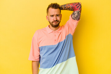 Young tattooed caucasian man isolated on yellow background suffering neck pain due to sedentary lifestyle.