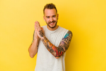 Young tattooed caucasian man isolated on yellow background feeling energetic and comfortable,...