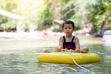 Little  girl sitting in inflatable tube against streams background.