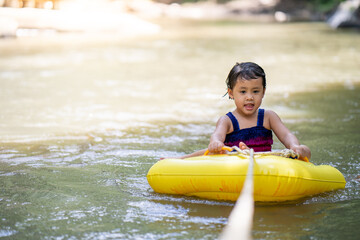 Little  girl sitting in inflatable tube against streams background.