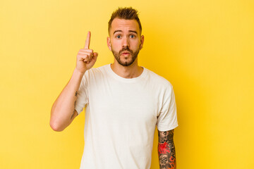 Fototapeta premium Young tattooed caucasian man isolated on yellow background pointing upside with opened mouth.