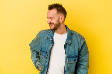 Young tattooed caucasian man isolated on yellow background laughs and closes eyes, feels relaxed and happy.