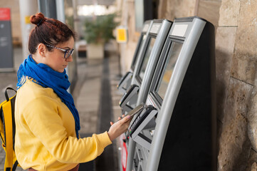 Close-up of a woman paying at a self-service machine using a contactless phone payment - obrazy, fototapety, plakaty