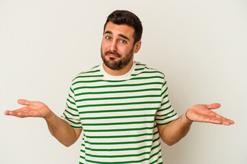 Young caucasian man isolated on white background doubting and shrugging shoulders in questioning...