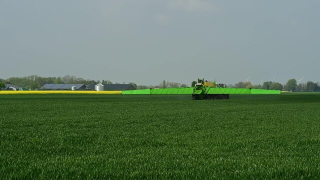 Traktor mit Feldspritze beim Ausbringen von Pflanzenschutzmittel gegen Pestizid