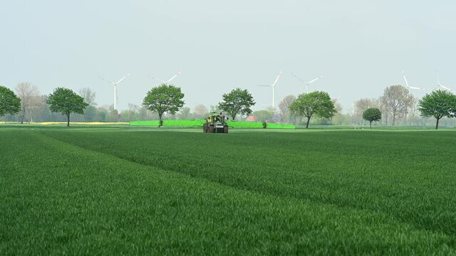 Traktor mit Feldspritze beim Ausbringen von Pflanzenschutzmittel gegen Pestizid