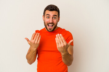 Young caucasian man isolated on white background pointing with finger at you as if inviting come closer.