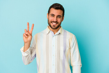 Naklejka premium Young caucasian man isolated on blue background showing victory sign and smiling broadly.