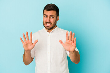 Young caucasian man isolated on blue background rejecting someone showing a gesture of disgust.