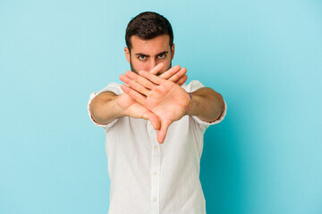 Young caucasian man isolated on blue background doing a denial gesture