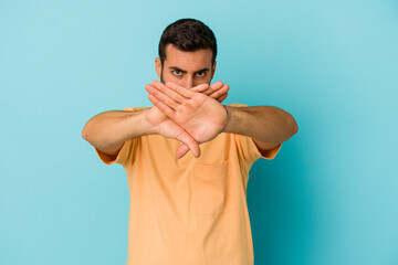 Young caucasian man isolated on blue background doing a denial gesture