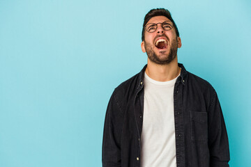 Obraz premium Young caucasian man isolated on blue background shouting very angry, rage concept, frustrated.