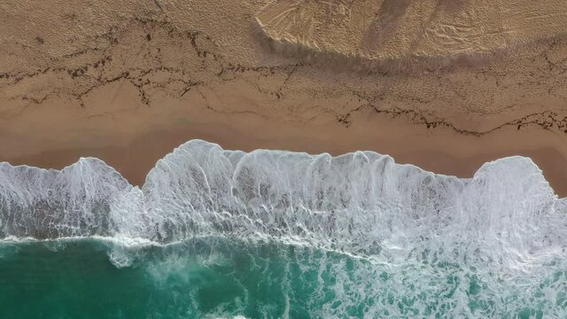 Vue a&eacute;rienne de drone de vagues s'&eacute;chouant sur une plage de sable au lever du soleil &agrave; Carg&egrave;se, en Corse - Top aerial static view in Corsica, Carghjese