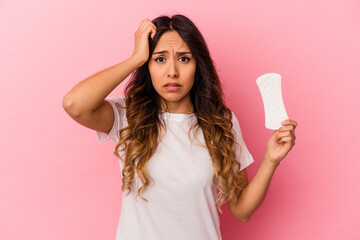 Young mexican woman holding a compress isolated on pink background being shocked, she has remembered important meeting.