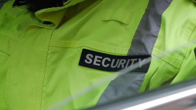 A closeup of security personnel in a neon-green safety jacket sitting inside a car in HD