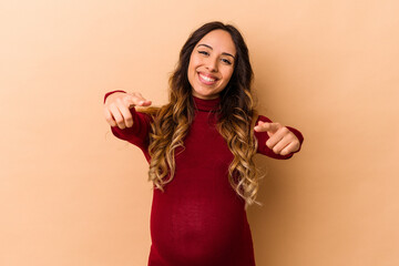 Young mexican pregnant woman isolated on beige background cheerful smiles pointing to front.