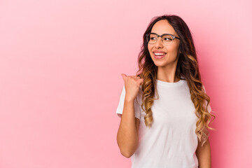Young mexican woman isolated on pink background points with thumb finger away, laughing and carefree.