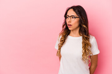 Young mexican woman isolated on pink background being shocked because of something she has seen.