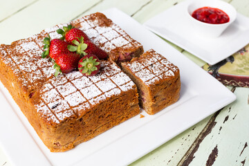 Square Raspberry and yoghurt cake with cut slice on white plate