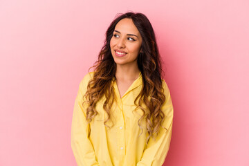 Fototapeta premium Young mexican woman isolated on pink background looks aside smiling, cheerful and pleasant.
