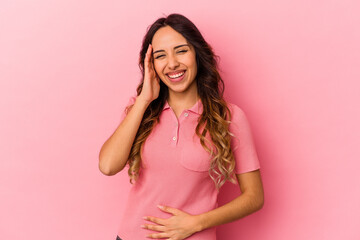 Young mexican woman isolated on pink background laughs happily and has fun keeping hands on stomach.