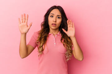 Young mexican woman isolated on pink background being shocked due to an imminent danger