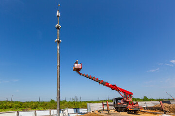 Engineer starts working on the telecommunication tower  from aerial work platform, also known as an...
