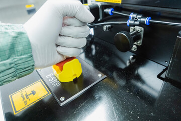 male hand wearing gloves presses an emergency button of an industrial machine
