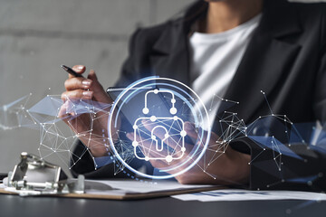 Businesswoman in formal wear signing the contract to prevent probability of risks in cyber security. Checking the phone. Padlock Hologram icons over the working desk.