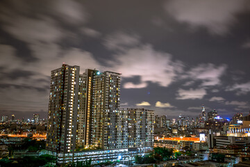 Obraz premium The high angle background of the city view with the secret light of the evening, blurring of night lights, showing the distribution of condominiums, dense homes in the capital community