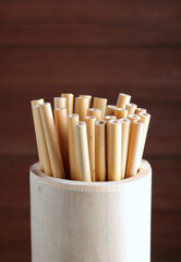 bamboo straw in bamboo cylinder on wood background with copy space ( straw from natural material / green product concept )