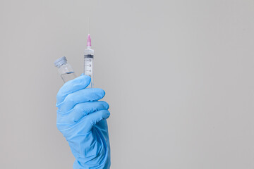 coronavirus vaccine in blue gloves holding holding syringe and bottle with vaccine for covid-19 cure. The weapons used to fight the coronavirus are vaccines and syringes in the hands of doctors.